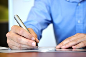 man signing paper copy